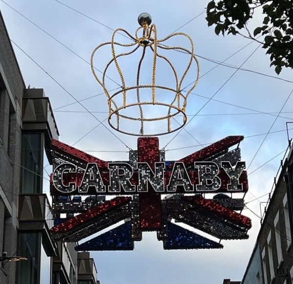 Carnaby Street sign with Union Jack design and illuminated crown decoration in London's Soho district