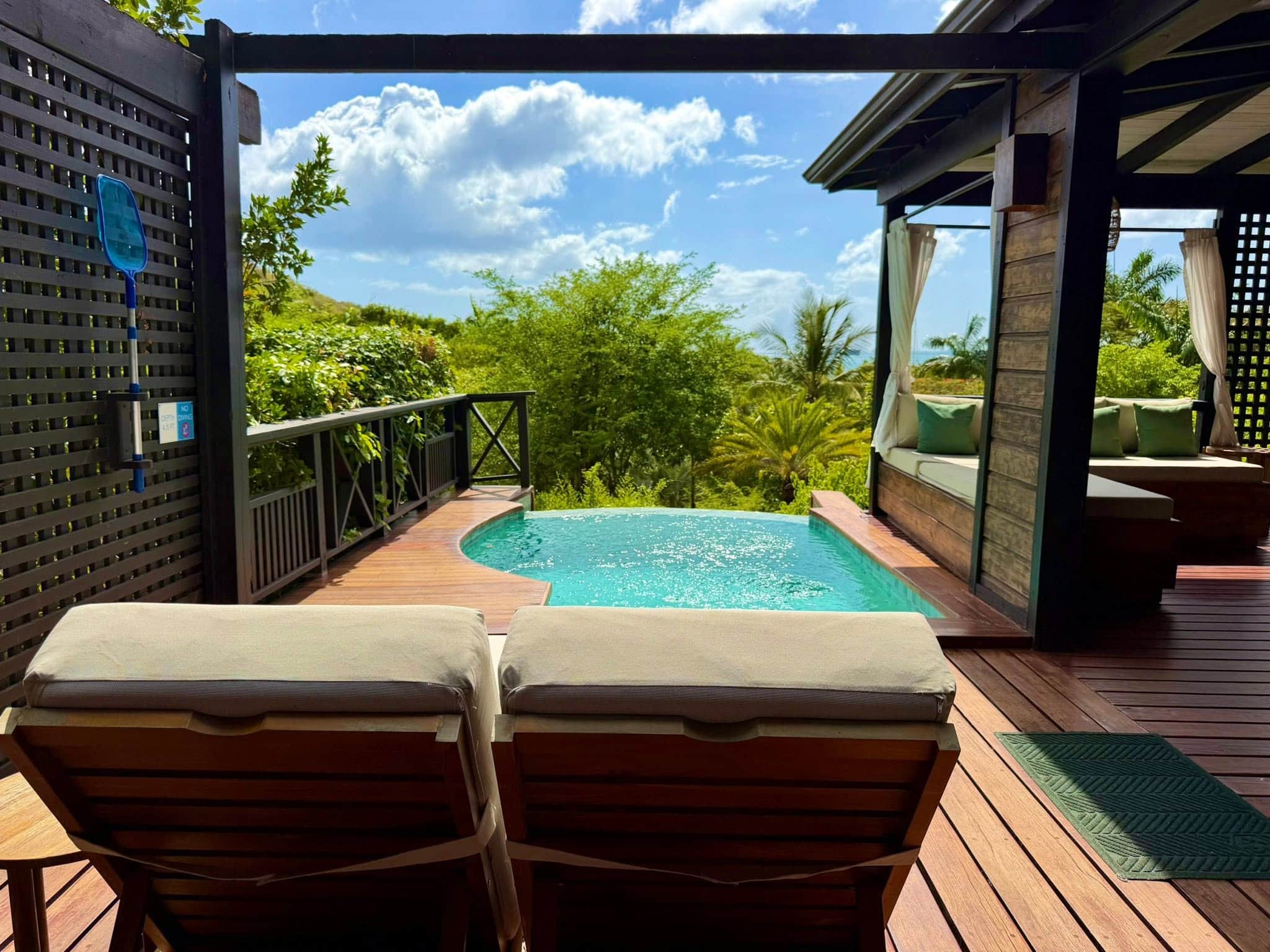 Private plunge pool and outdoor deck at a Hillside Garden Pool Villa at Hermitage Bay Antigua, featuring lounge chairs and tropical garden views.
