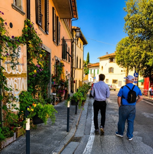 Father and son walking along a colorful street in Siena, Tuscany during a family trip to Italy