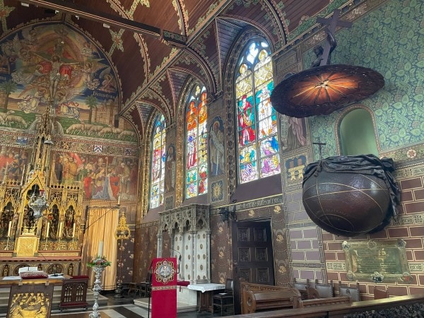 Interior of the Basilica of the Holy Blood in Bruges, Belgium featuring stained glass windows and Gothic architecture