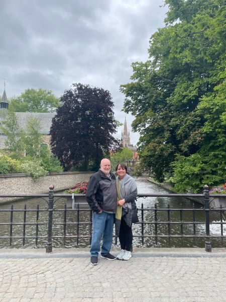 Couple standing beside a canal in Bruges, Belgium during a European anniversary trip