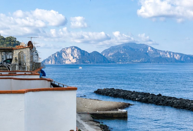 View of the Isle of Capri from an Airbnb terrace in Massa Lubrense, Italy, overlooking the Bay of Naples along the Amalfi Coast.