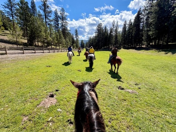 Guests enjoying a guided horseback ride through the scenic Montana landscape at RiverView Ranch Retreat & Western Adventures, an all-inclusive luxury guest ranch bookable with Hilton Honors points.