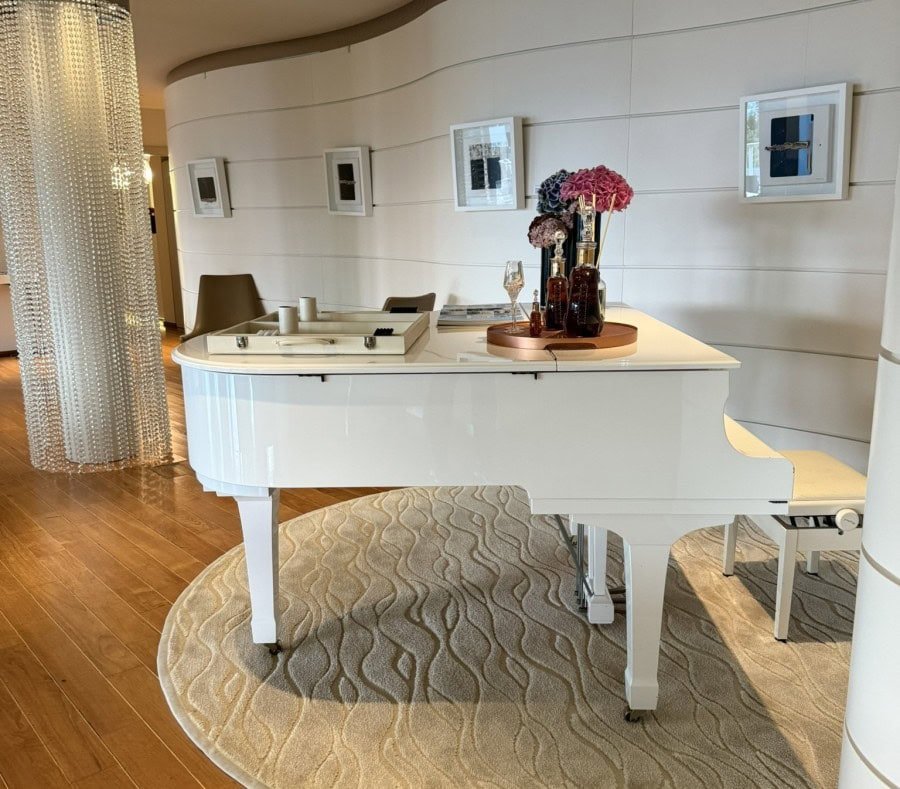 Elegant hotel lounge overlooking Lake Lugano with a white grand piano, modern décor, and a relaxing atmosphere.