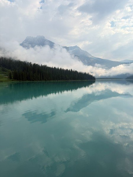 Clouds and mountain reflections on calm turquoise water at Emerald Lake in Yoho National Park