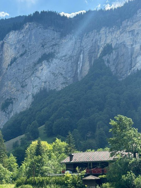 Steep cliffs and a waterfall above trees in Lauterbrunnen
