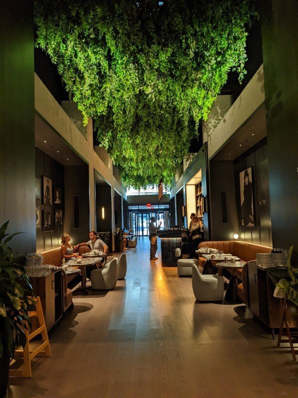 Parker’s restaurant at Thompson Central Park New York with hanging greenery, lounge seating, and dining tables.