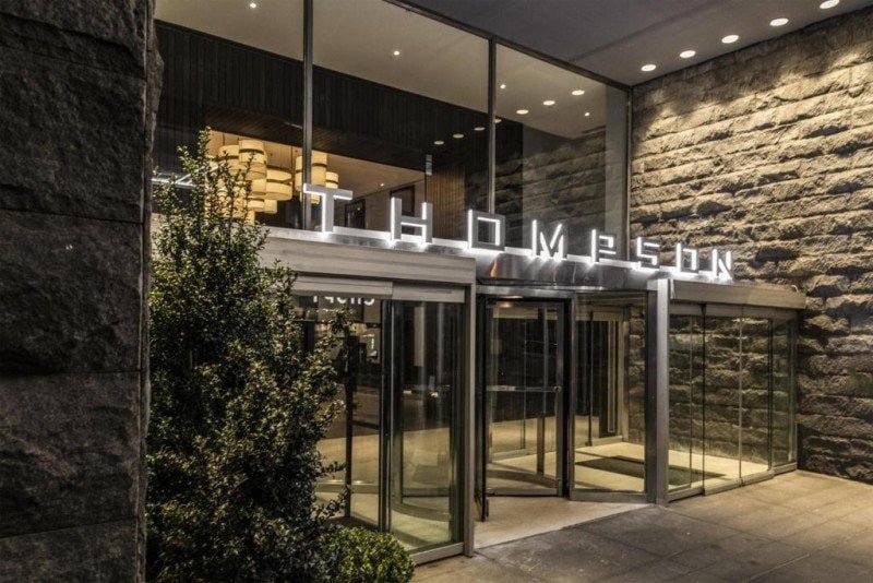 Thompson Central Park New York entrance with revolving glass doors and illuminated Thompson signage.
